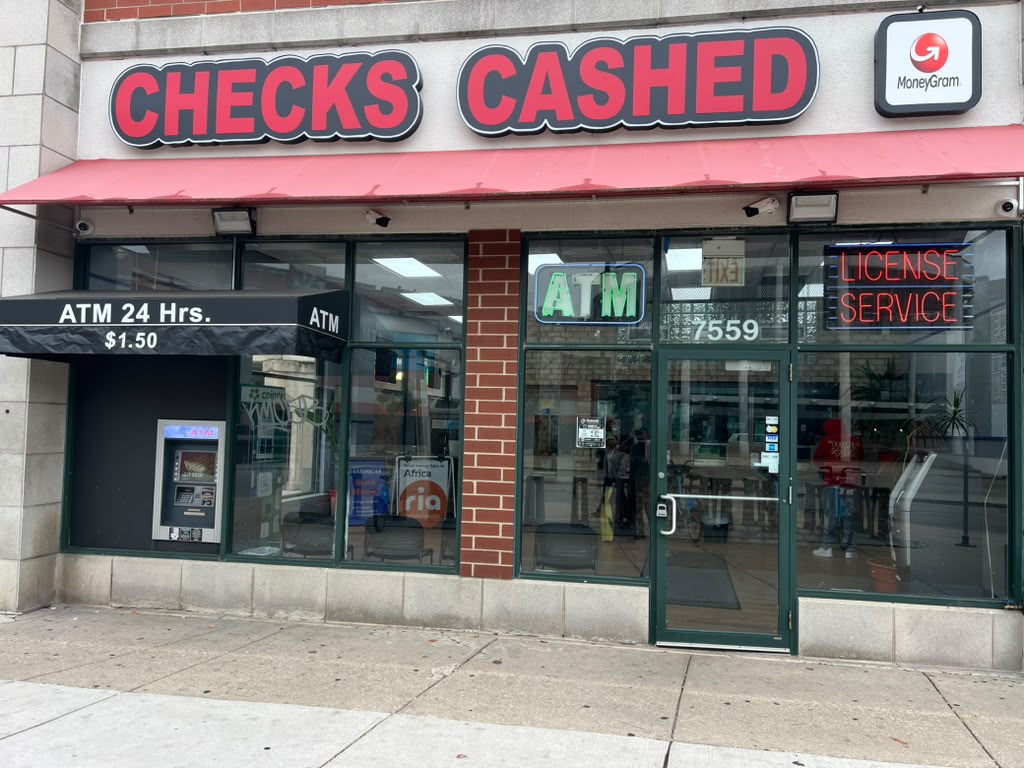 Front entrance of New Howard Currency Exchange at 7559 N Paulina St with Checks Cashed sign and 24-hour ATM
